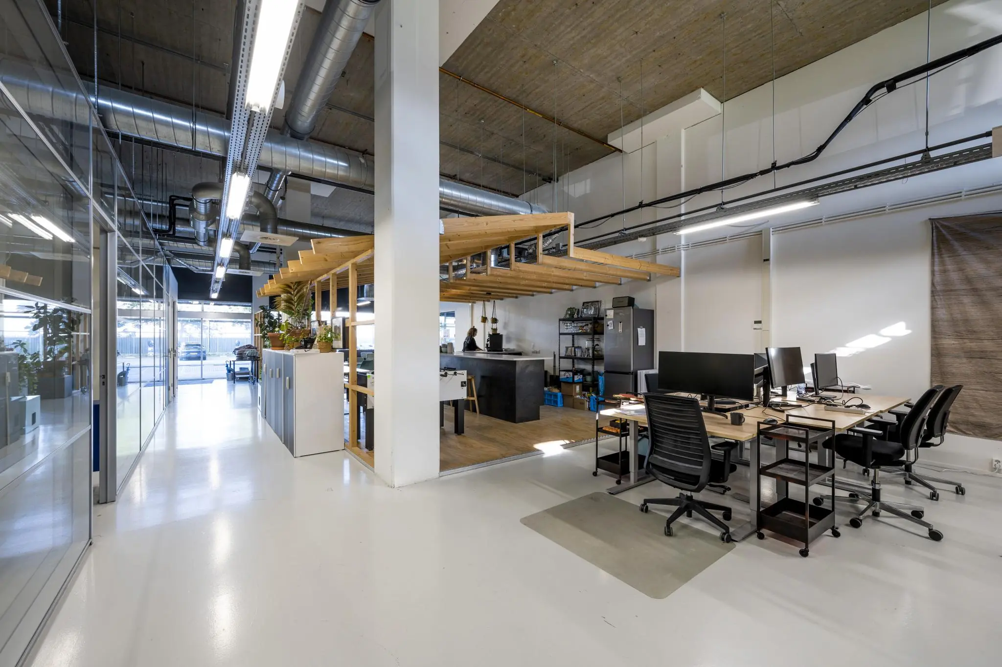 Modern kantoorinterieur aan de Joan Muyskenweg met open werkplekken, industriële details en een centraal gelegen pantry.